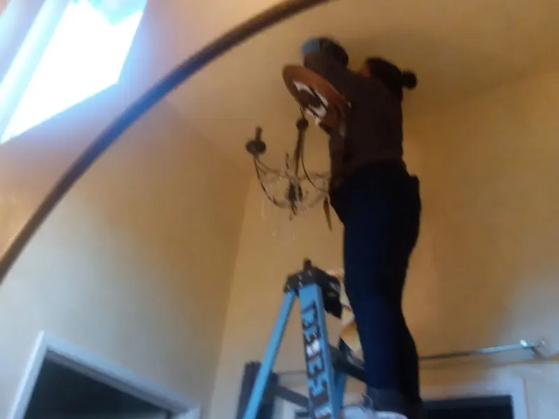 Electrician installing a chandelier in a Herkimer residence